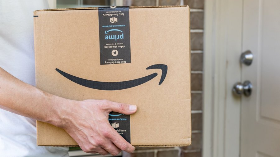 Mann hält Amazon-Paket vor Haustür