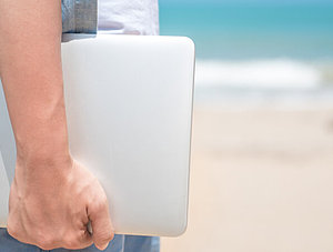 Mann mit Laptop am Strand