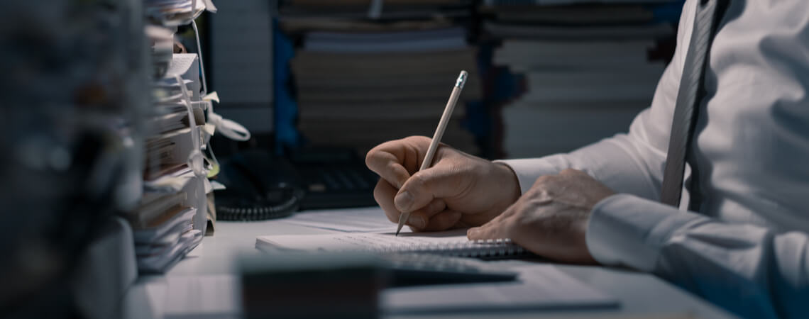 Hand schreibt mit Bleistift auf Papier