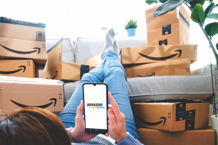 Frau liegt vor Sofa voller Amazon-Kartons