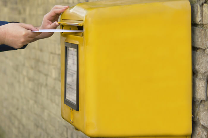 Mann steckt Brief in Briefkasten