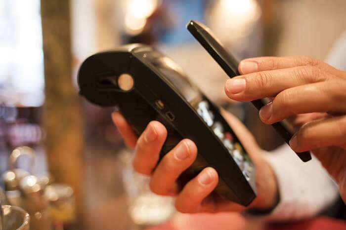 Man paying with NFC technology on mobile phone, in restaurant, bar, cafe