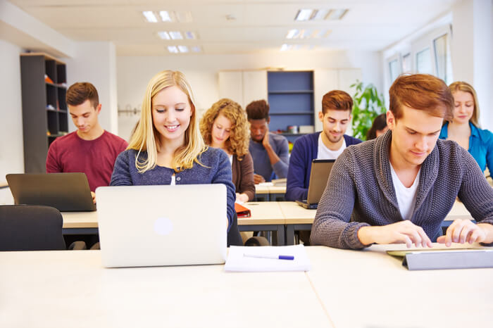 Studenten in der Schule an Laptops und Tablets 