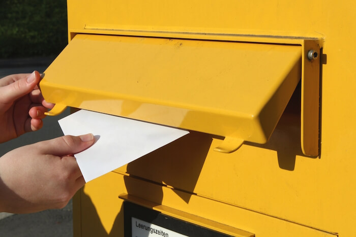 Brief wird in einen Briefkasten gesteckt