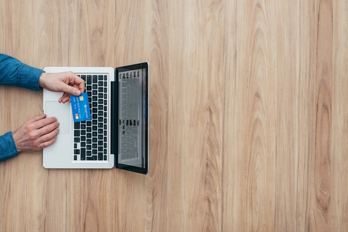 Man working at desk and purchasing products online, he is making a payment using a credit card