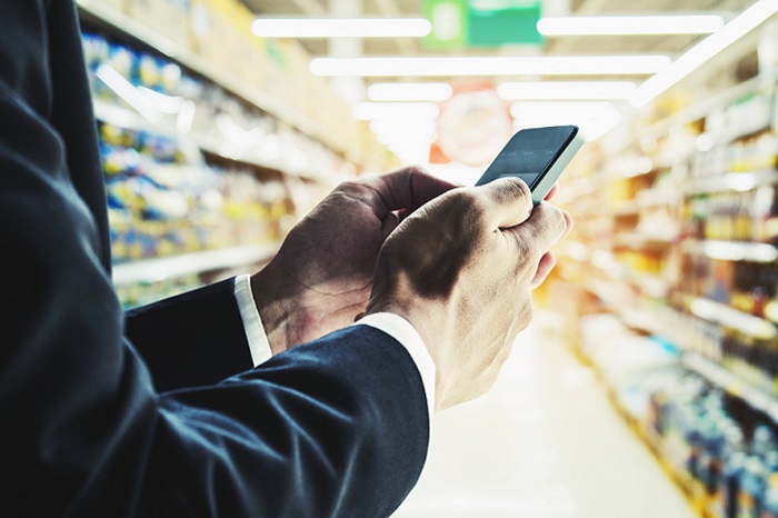 Geschäftsmann mit Smartphone im Laden