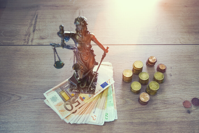 Justitia steht auf einem Tisch mit Geld 