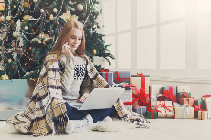 Frau mit Laptop unter Weihnachtsbaum